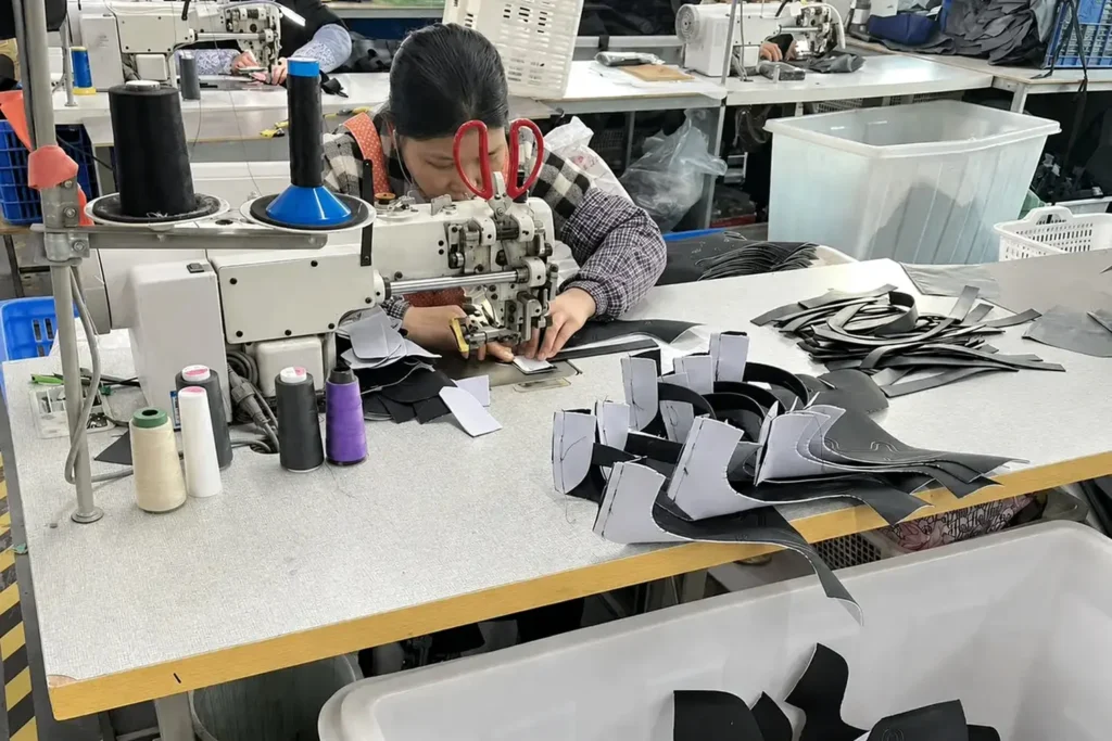Worker sewing bag components during backpack production